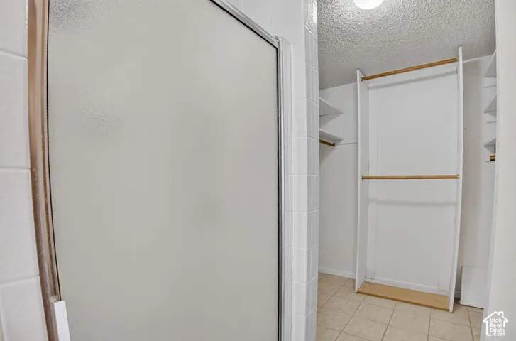 Frosted glass shower enclosure, white tiled walls, built-in shelving, and hanging rods