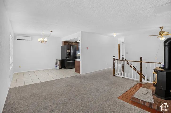 Open-concept living area featuring a tile dining space, wood-finish staircase with white spindles, and a built-in wood-burning stove with a brick hearth