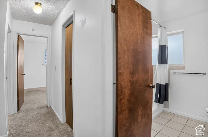 Hallway with textured ceiling and wall-to-wall carpeting