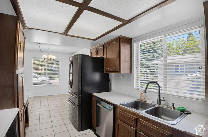 Kitchen featuring wood cabinetry, white countertops, a stainless steel double basin sink, and a black refrigerator
