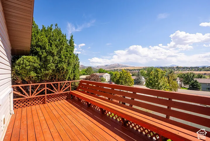 Elevated wood deck with a built-in bench, lattice railing, and a distant mountain backdrop