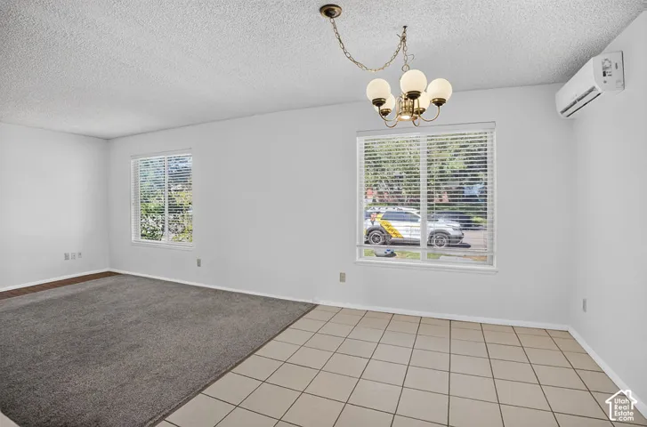 Recessed lighting, white walls, two windows with blinds, mini-split air conditioning unit, and a chandelier