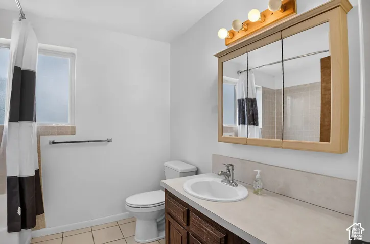 Vanity with integrated sink, wood-finish cabinetry, and neutral countertop