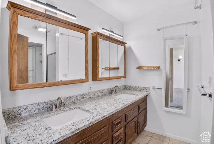 Dual wood-finish medicine cabinets, white rectangular undermount sinks, speckled stone-finish countertop, and wood-finish vanity