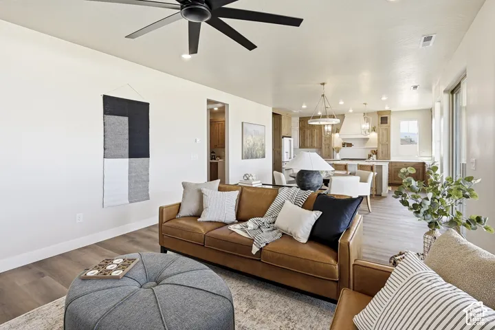 Open-concept living area featuring a black ceiling fan, recessed lighting, and wood-finish flooring