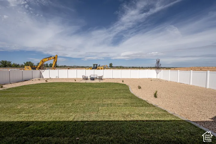 Expansive backyard featuring a white privacy fence, manicured lawn, and gravel landscaping