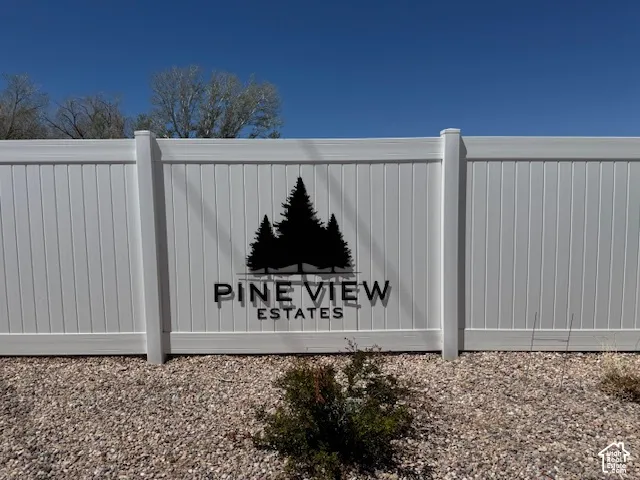 White vinyl fence with a decorative dark sign featuring trees and text