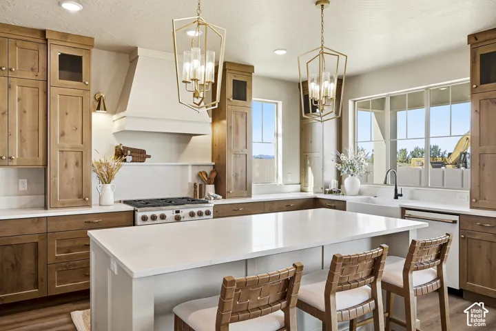 Expansive kitchen featuring light wood-finish cabinetry, a large center island with a light-toned countertop, and dual geometric pendant lights