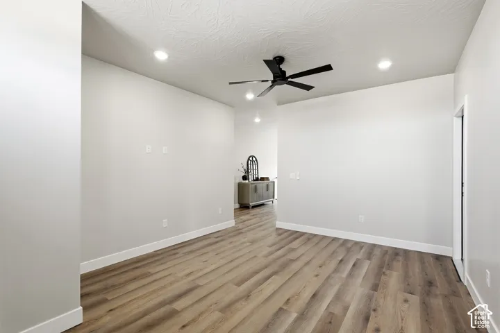Wood-finish flooring, recessed lighting, ceiling fan, white baseboards, and light-toned walls