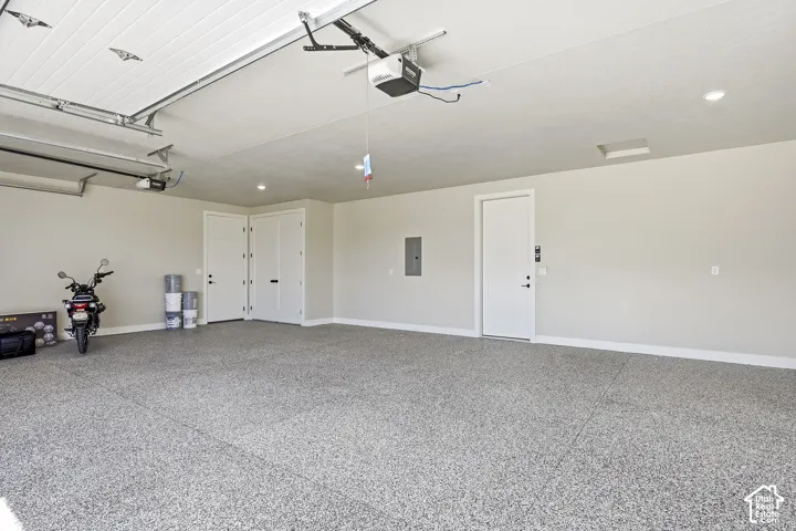 Spacious garage featuring a speckled epoxy floor, white paneled garage doors, and recessed lighting