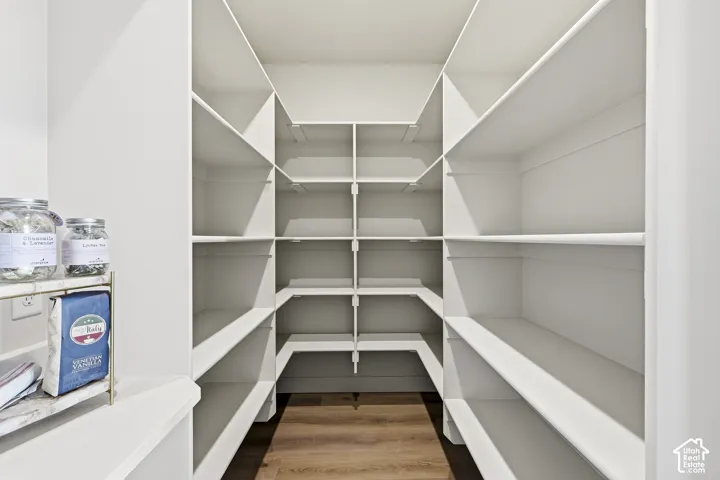 Expansive pantry with built-in white shelving, wood-finish flooring, and a countertop surface