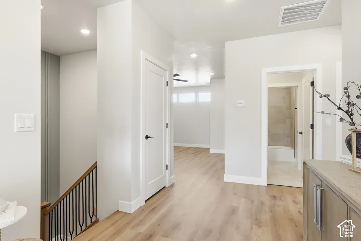 Wood-finish flooring, recessed lighting, white interior doors, and a staircase with a wood handrail and black metal spindles