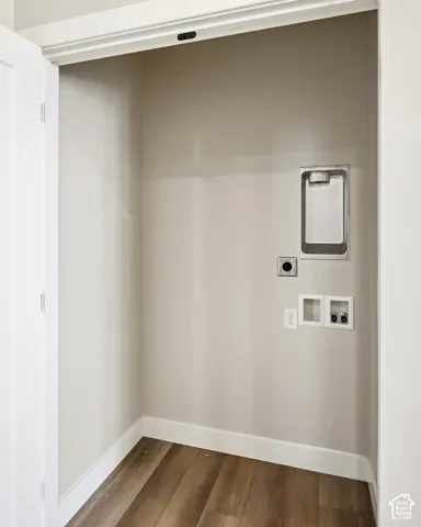 Dedicated laundry closet with wood-finish flooring, built-in utility sink, and electrical outlets