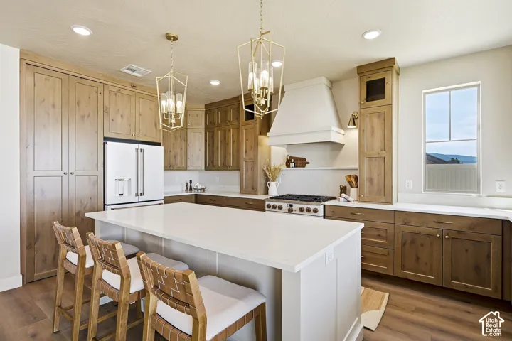 Kitchen featuring a large island with counter seating, wood-finish flooring, recessed lighting, and stylish pendant light fixtures
