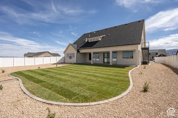 Expansive backyard featuring a manicured lawn, gravel landscaping, and a privacy fence