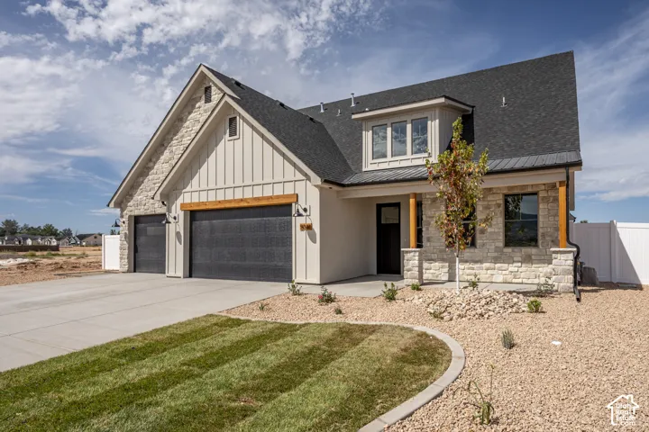 Modern farmhouse exterior featuring board and batten siding, stone accents, two-car garage, and a covered entry