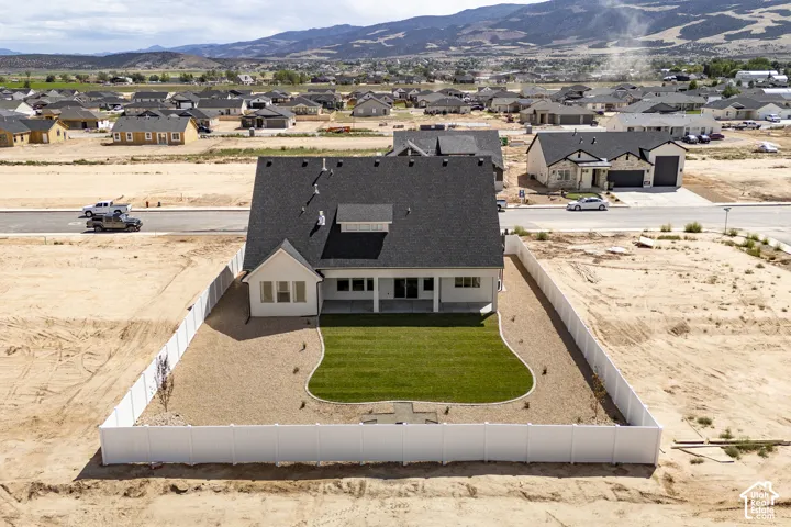 Rear exterior featuring a white vinyl privacy fence, a manicured lawn, and a covered patio