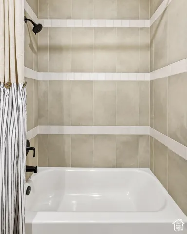 Bathtub with tile surround, decorative tile bands, and matte black fixtures