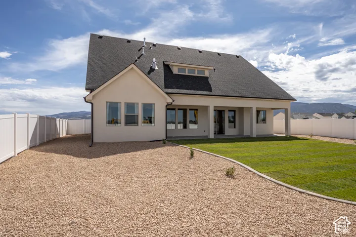 Exterior stucco finish, dark shingle roofing, dormer window, covered patio, and a privacy fence