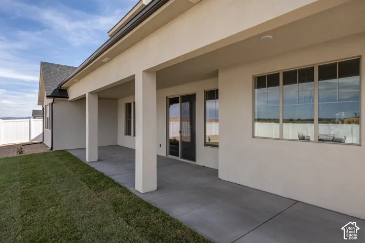 Covered patio with a concrete surface, stucco exterior, multiple windows, and a sliding glass door