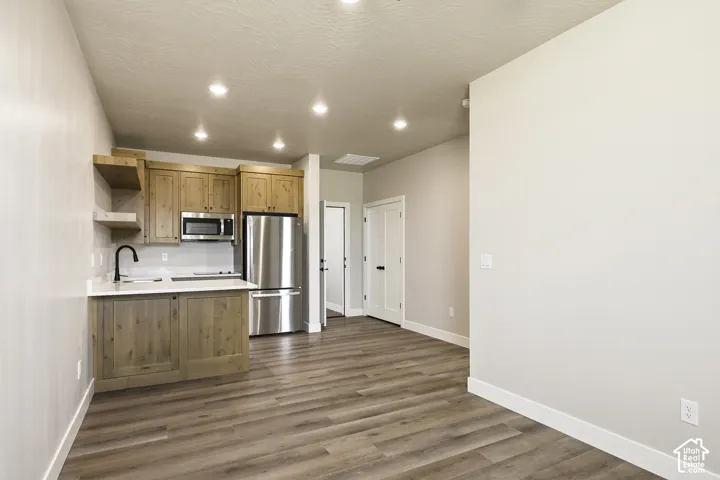 Kitchenette featuring wood cabinetry, stainless steel appliances, white countertops, and a black gooseneck faucet