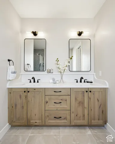 Dual vanity with wood-finish cabinetry, white countertop, and integrated sinks