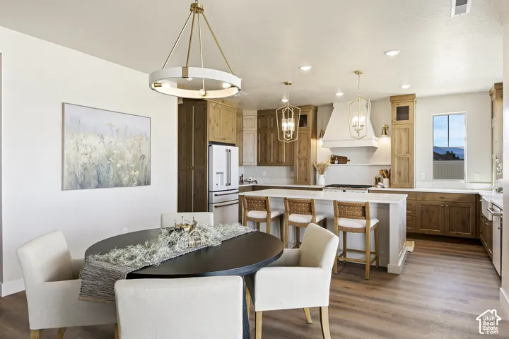 Open-concept living space featuring wood-finish flooring, a kitchen island with seating, pendant lighting, and recessed lighting