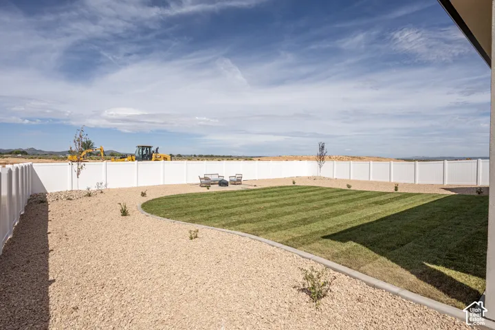 Expansive fenced backyard featuring a manicured lawn, gravel landscaping, and a substantial privacy fence