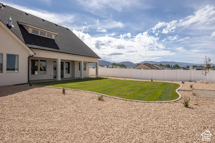 Modern home featuring a professionally landscaped backyard with curved lawn borders, decorative gravel hardscaping, and young plantings