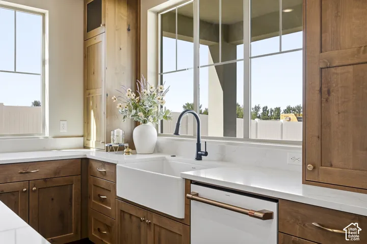Farmhouse sink with a matte black gooseneck faucet, white quartz countertops, and rich wood cabinetry