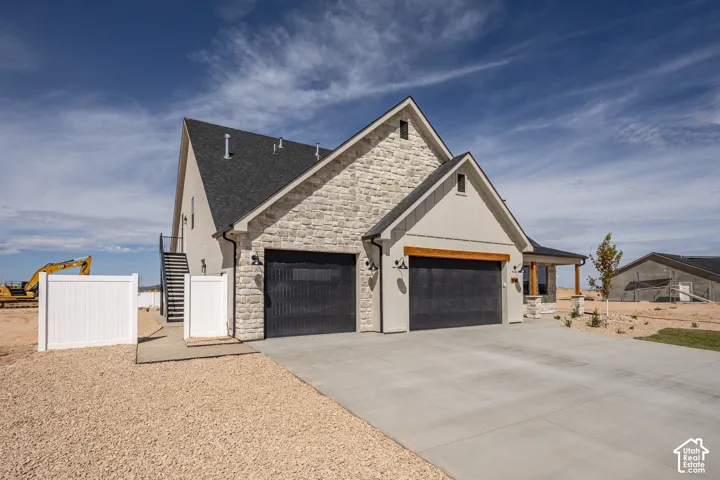 Modern exterior featuring a stone and board-and-batten facade, a dark shingle roof, and a concrete driveway