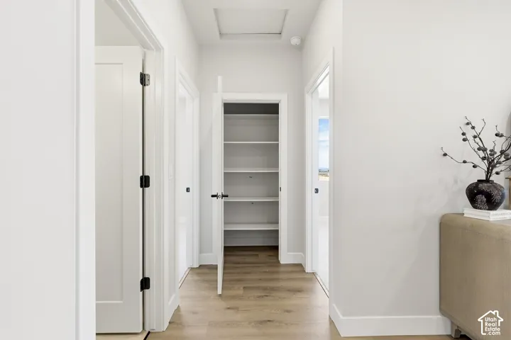Hallway with wood-finish flooring, white walls, and bright overhead lighting