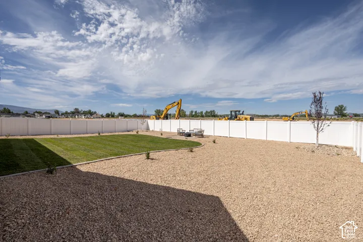 Expansive backyard featuring a manicured lawn, gravel landscaping, and privacy fencing