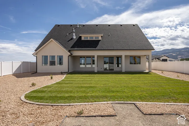 Expansive backyard featuring a manicured lawn, gravel landscaping, and a covered patio