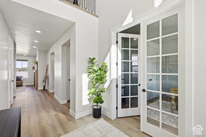 Bright hallway featuring wood-finish flooring, recessed lighting, and a visible second-story railing