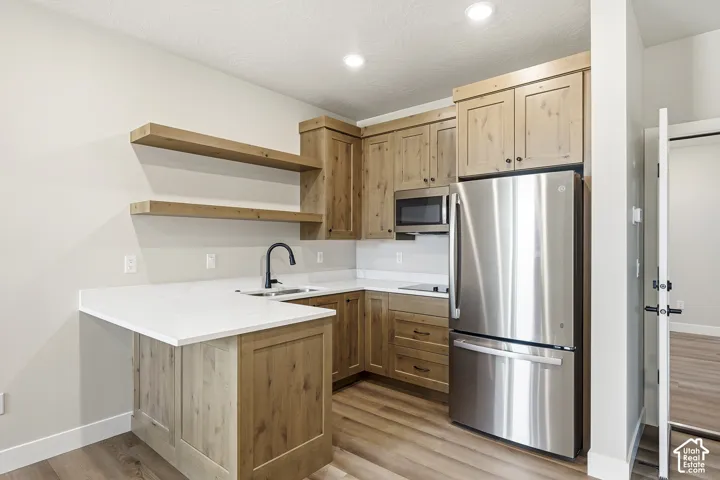 U-shaped kitchen featuring wood-finish cabinetry, white countertops, and stainless steel appliances