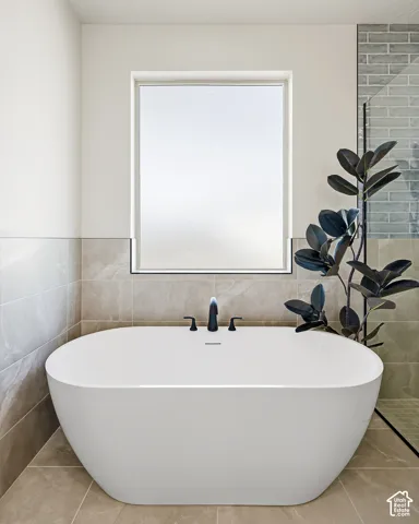 Freestanding soaking tub with matte black fixtures, set against a tiled wall and floor