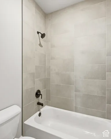 White bathtub with dark bronze fixtures and full height tiled surround