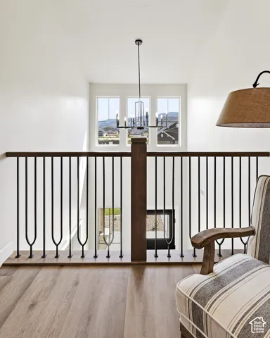 Open-concept landing with wood-finish flooring, wrought iron and wood railing, and a modern chandelier