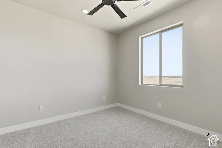Recessed ceiling light, ceiling fan, neutral wall color, light gray carpet, and a large window
