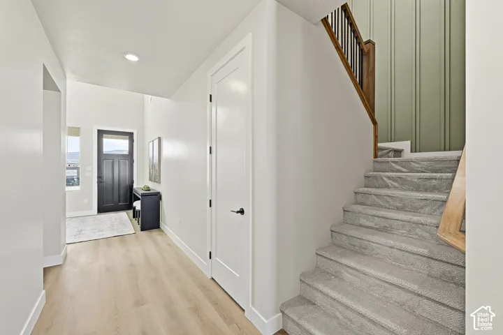 Wood-finish flooring, recessed lighting, and a dark paneled entry door
