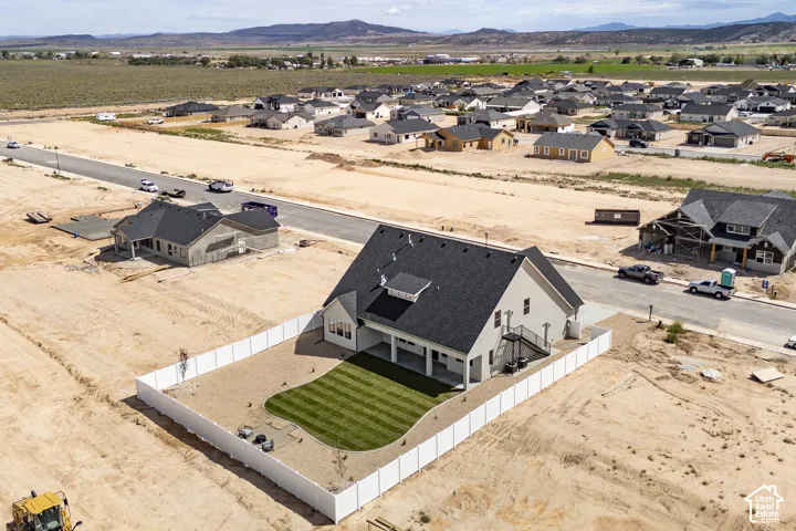 Newly constructed residence featuring a white vinyl perimeter fence, a manicured lawn, and a covered back patio