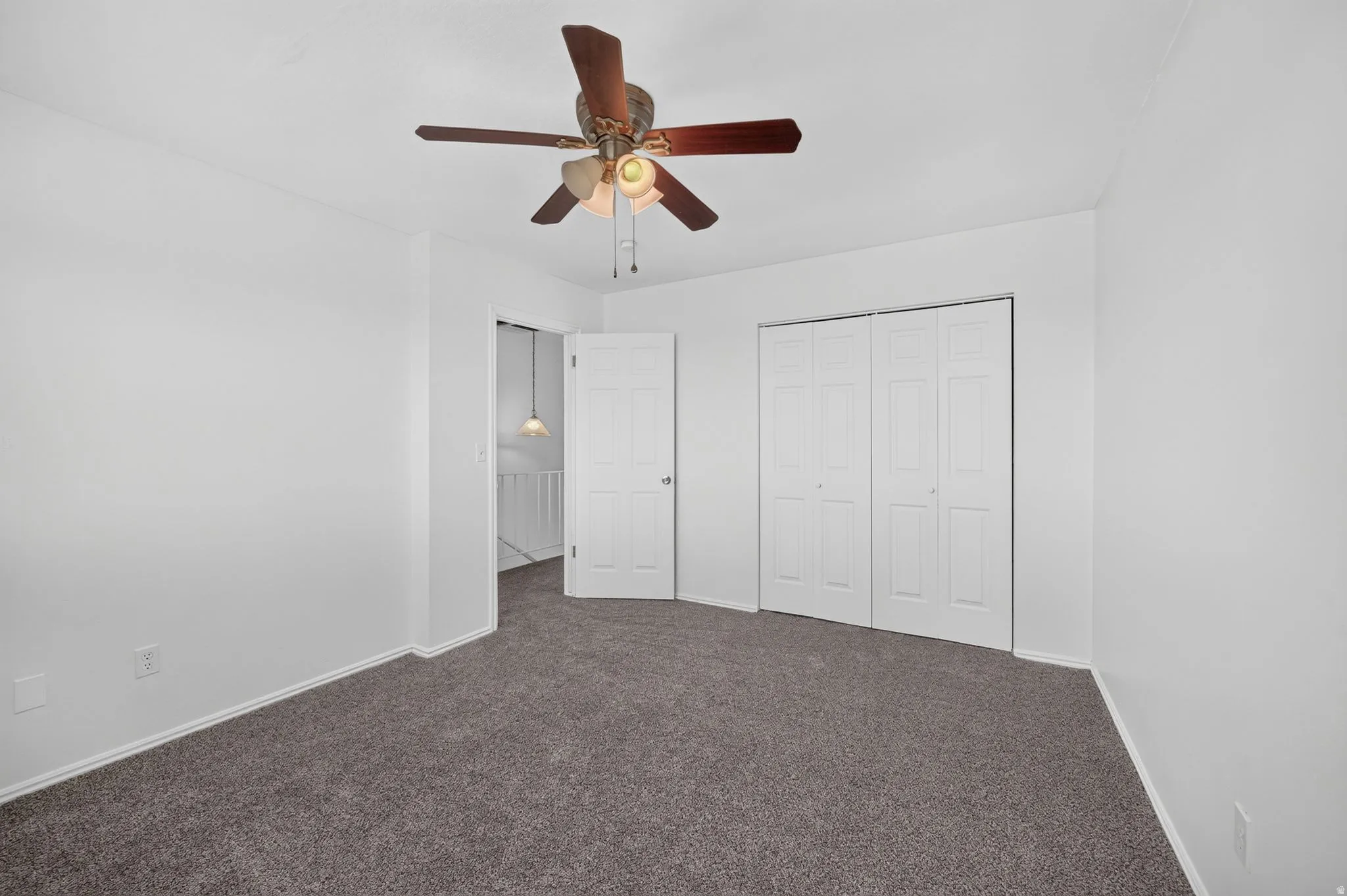 Neutral wall finishes, textured carpet flooring, and a ceiling fan with integrated lighting