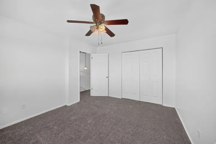 Neutral wall finishes, textured carpet flooring, and a ceiling fan with integrated lighting