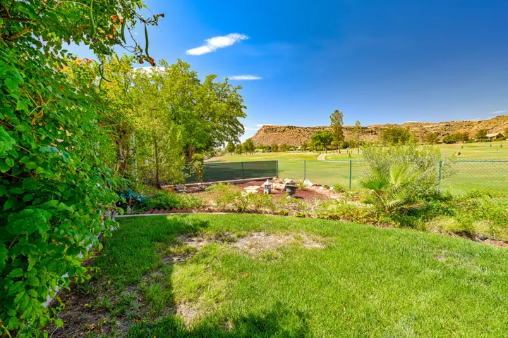 Expansive green space with mature trees, a manicured lawn, and a natural rock formation backdrop