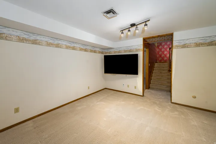 Recessed ceiling, track lighting fixture, and neutral carpeting