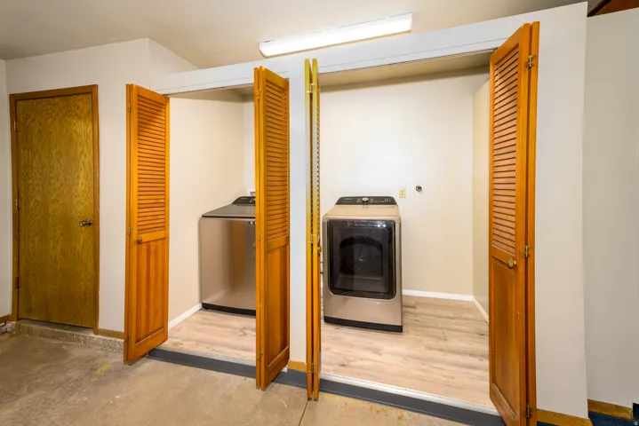 Laundry closet with louvered bi-fold doors and wood-finish flooring