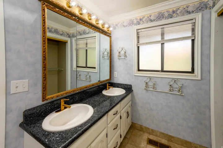 Dual vanity with integrated sinks, gold-tone faucets, and a dark speckled countertop