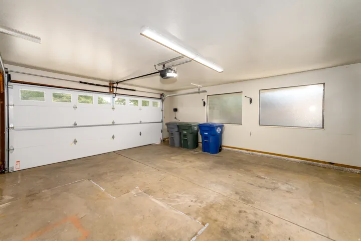 Attached garage with a sectional overhead door, automatic opener, two translucent windows, and fluorescent lighting