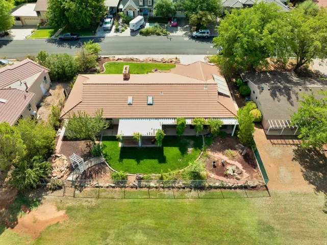 Tile roof, rear patio with pergola, solar panels, and a landscaped backyard featuring a manicured lawn